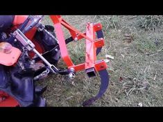 a red and black machine is sitting in the grass with it's handle extended