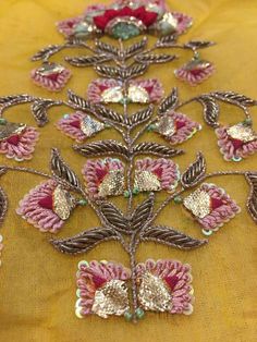 an embroidered table cloth with flowers and leaves on the top, along with beading