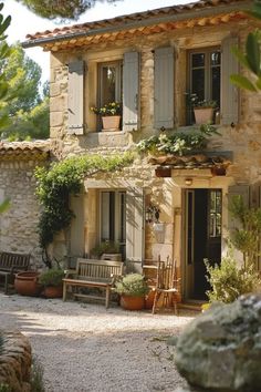 an old stone house with potted plants on the windows