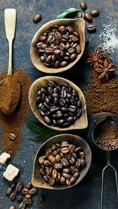 three spoons filled with different types of coffee beans and spices on top of a table