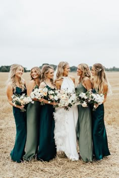 the bride and her bridesmaids are standing in a field with their bouquets