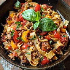 a bowl filled with pasta, meat and veggies on top of a wooden table