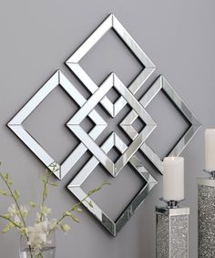 a decorative wall mirror on the wall next to a vase with white flowers and candles