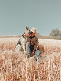 a woman and her dog are sitting in the middle of a wheat field with their noses to each other