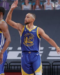 two basketball players in blue and yellow uniforms with their hands up to the air as they play against each other