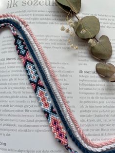 three braided bracelets sitting on top of an open book next to eucalyptus leaves