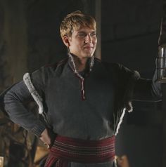 a man dressed in medieval clothing standing next to a lamp