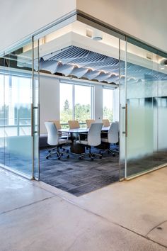 an empty conference room with glass walls and chairs