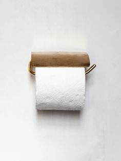 a roll of toilet paper sitting on top of a white wall next to a gold handle