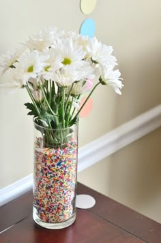 a vase filled with white flowers and sprinkles on top of a table