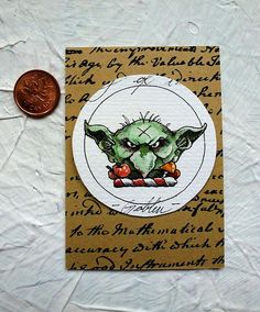 a penny sitting on top of a piece of paper next to a sticker with an image of a baby yoda