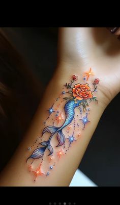 a woman's arm with a rose and fish tattoo on it, which is decorated with stars