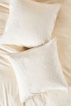 two white pillows sitting on top of a bed