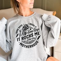 a woman sitting in a chair with her hands on her hips wearing a sweatshirt that says it rocks me