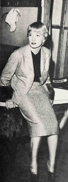 an old photo of a woman in a skirt and blazer posing for the camera