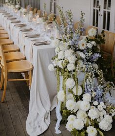 a long table with white and blue flowers on it is set up for an event