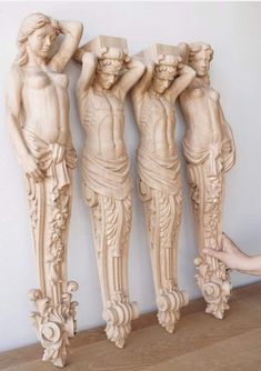 three carved wooden statues sitting next to each other on top of a wood flooring board