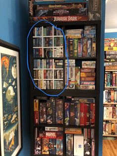 a book shelf filled with lots of books next to a framed poster on the wall