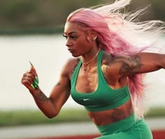 a woman with pink hair and tattoos running