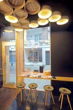 the interior of a restaurant with wooden tables and stools in front of a window