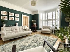 a living room with green walls and white furniture in the center, along with an area rug on the floor