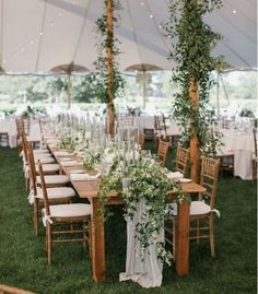 an outdoor tent with tables and chairs set up for a wedding reception in the grass