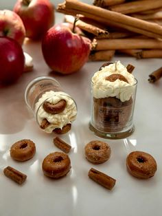 apples, cinnamon sticks and whipped cream are arranged on a white surface with cinnamons