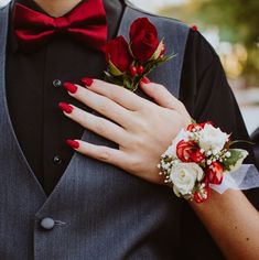 a man in a tuxedo with red and white flowers on his lapel