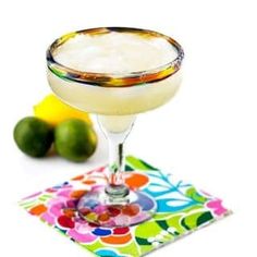 a margarita sitting on top of a colorful napkin next to limes