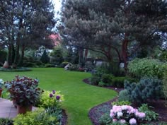 a lush green lawn surrounded by trees and flowers