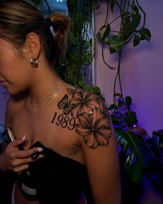 a woman with a flower tattoo on her shoulder looking at her cell phone in front of the camera