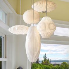 three white lamps hanging from the ceiling in a room with large windows and an ocean view