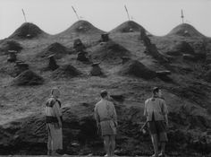 three men standing on top of a hill with lots of mounds in the back ground