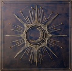 an intricately designed wall hanging in the shape of a sunburst on a brown background