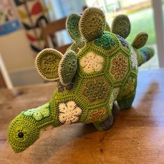 a green crocheted turtle sitting on top of a wooden table