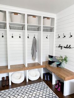 a mud room with white walls and wooden shelves