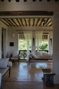 a living room filled with furniture and covered in white draping next to windows