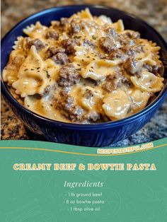 a blue bowl filled with pasta covered in meat and cheese on top of a granite counter