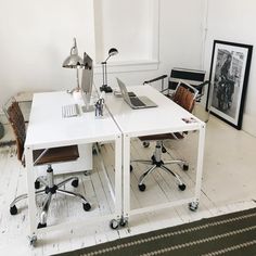 two white desks with chairs and a laptop on them in an empty room next to a window