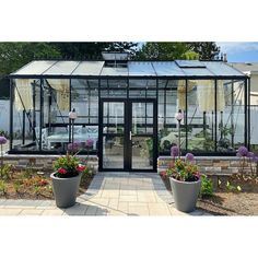 a glass house with potted plants in front of it