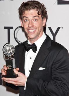 a man in a tuxedo holding an award for best performance at the tony awards