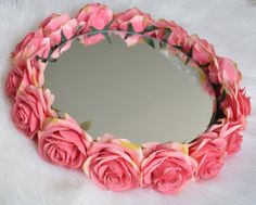 a mirror with pink roses on it sitting on a white furnishing area next to a wall