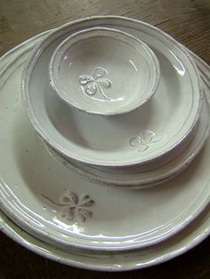 a stack of white plates sitting on top of a wooden table next to each other