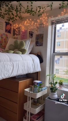 a bedroom with a bed, dresser and window covered in string lights that are hanging from the ceiling