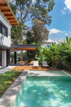 an outdoor swimming pool surrounded by greenery and wooden decking, with lounge chairs on the side