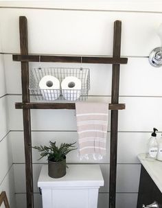 a white toilet sitting next to a wooden shelf with two rolls of toilet paper on it