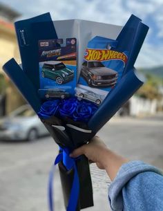 a person holding a bouquet of blue roses in front of a car with hot wheels stickers on it