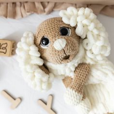 a stuffed animal with big eyes laying on a white blanket next to wooden pegs