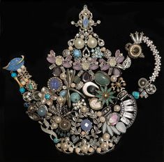 an elaborately decorated teapot with pearls, jewels and other things in it on a black background