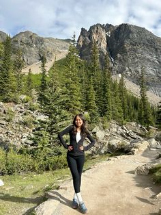 a woman standing on a trail in the mountains